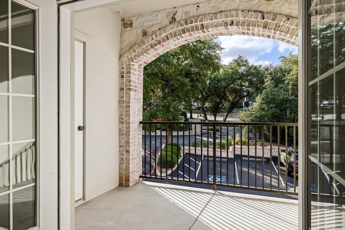 Covered patio framed by a brick archway with a greenbelt view, Barton Hollow, Westlake, Austin.