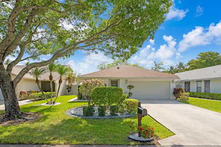 Single-story home with a two-car garage, broad driveway, and large shade tree over the front lawn.