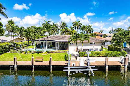 Waterfront home on a canal with a private dock and palm-lined lawn.