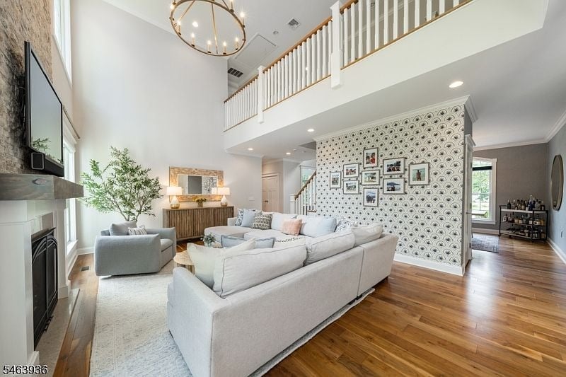 Double-height living room with a fireplace, white sectional, hardwood floors, and a patterned gallery wall.