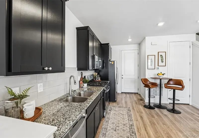 Modern kitchen at 2092 S Upham Way, Denver, CO 80227, featuring dark shaker cabinets, granite countertops, and wood-look flooring.