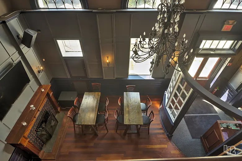 Furnished dining room with two long tables, a chandelier, and a fireplace.