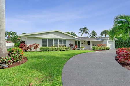 Single-story home with broad front windows, a curved driveway, and landscaped gardens.
