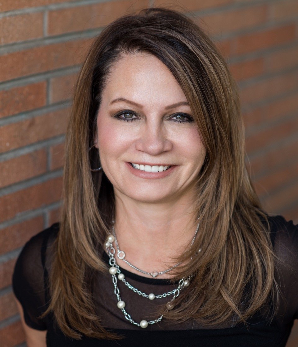 Debbie Rubio smiling in a headshot against a brick wall.