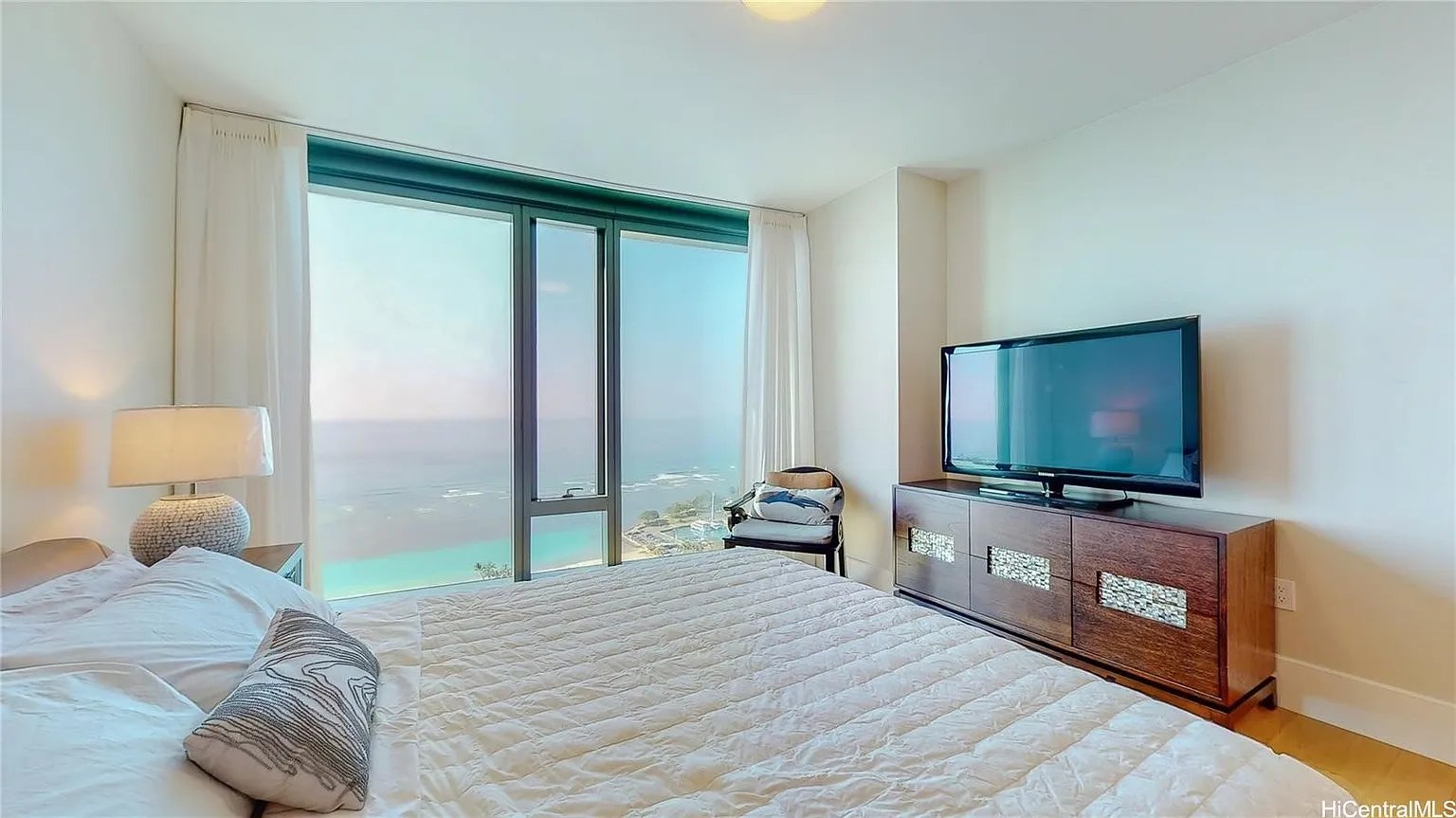 Bedroom with a large bed and floor-to-ceiling windows overlooking the ocean.