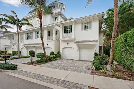 Attached white stucco homes with garage doors, palm trees, and landscaped front yards.