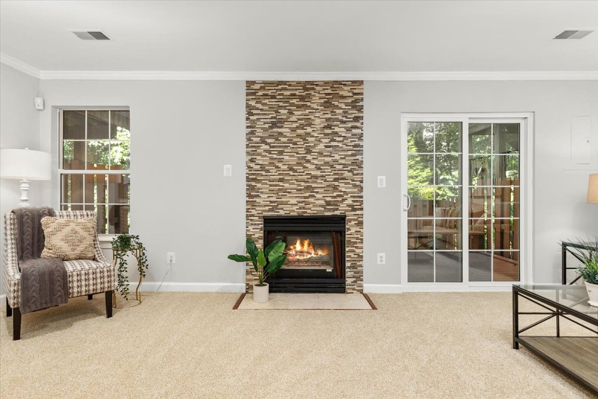 Living room with a tiled fireplace, beige carpet, and sliding glass doors to a patio.