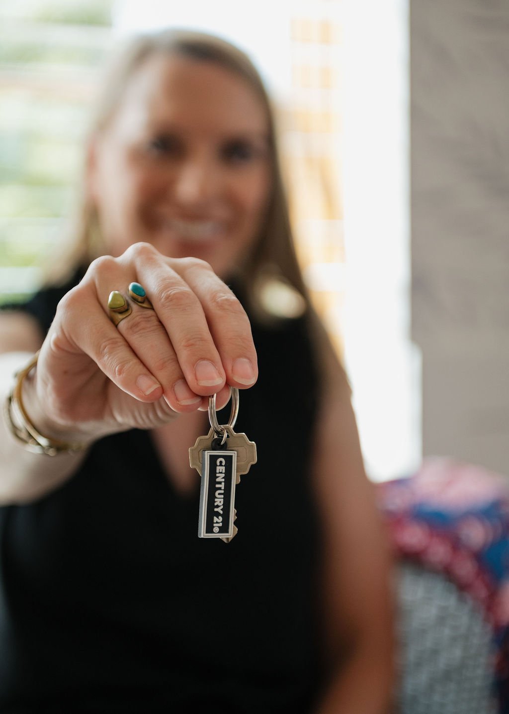 A woman holds out a key ring with a CENTURY 21 tag.