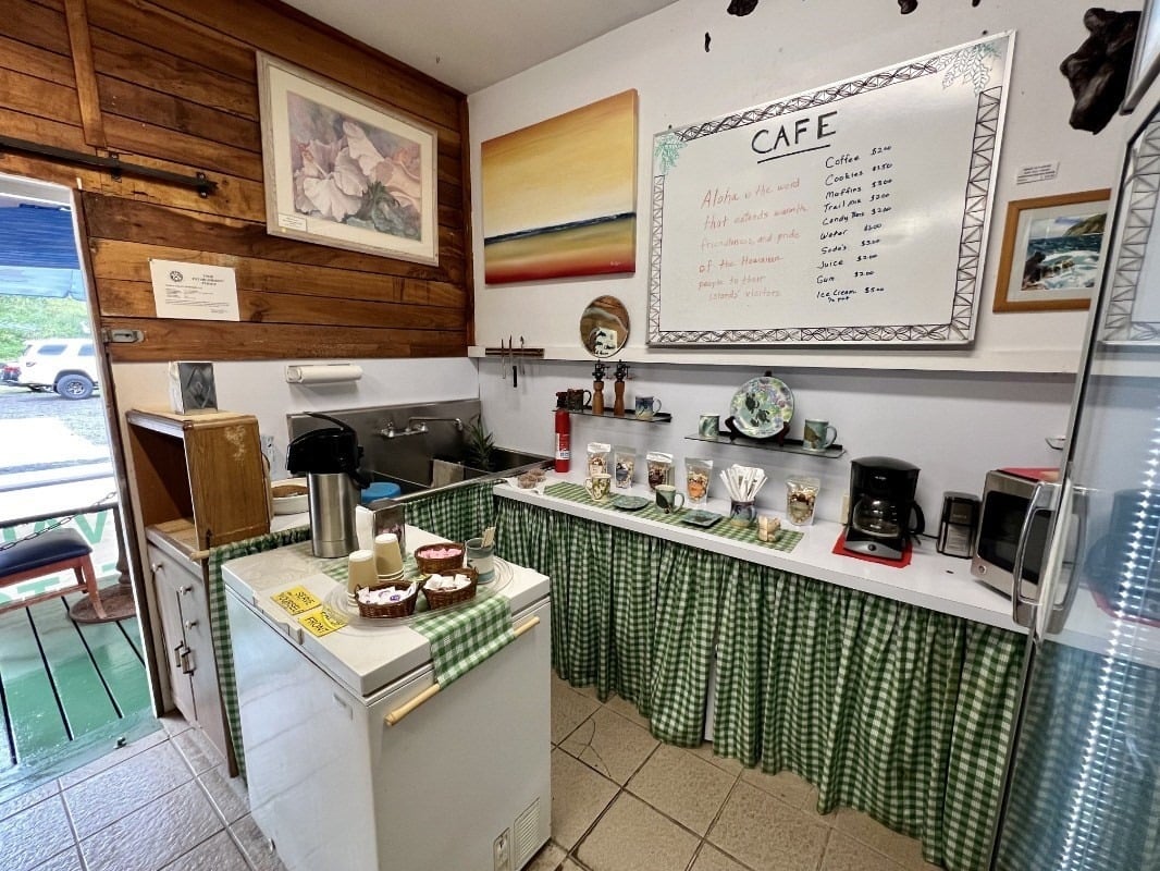 Cafe interior with a gingham-covered counter, coffee makers, and a handwritten menu board.