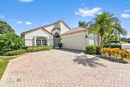Stucco home with an arched entry, attached garage, and wide brick-paver driveway.