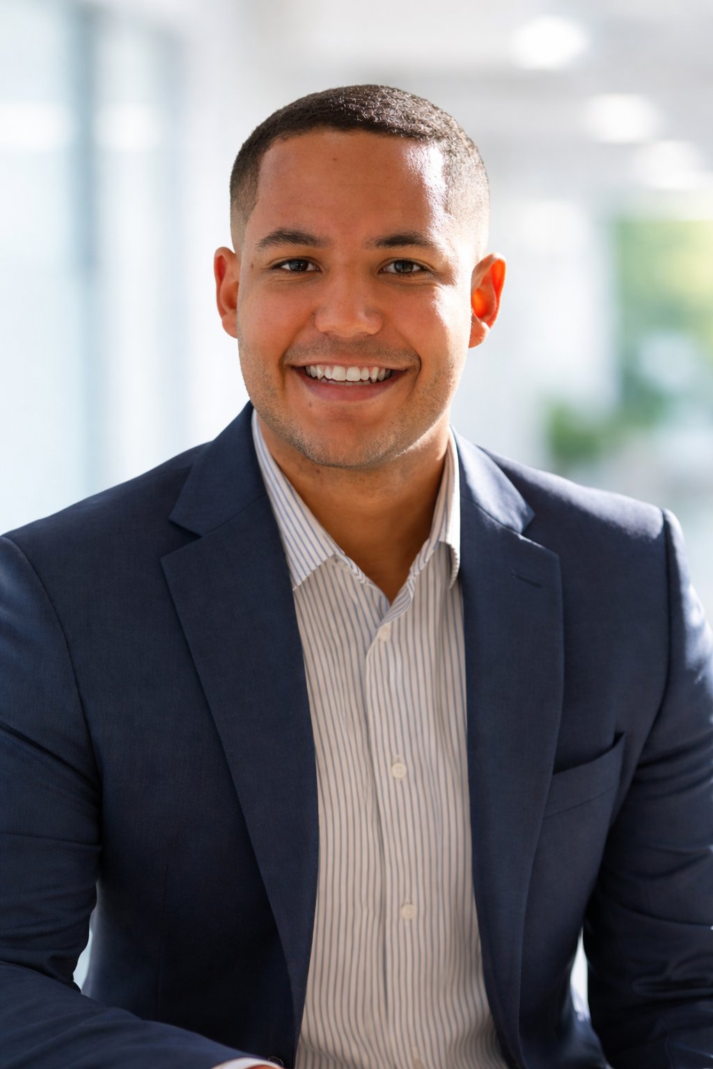 A.J. Graham smiles in a navy blazer and striped shirt.