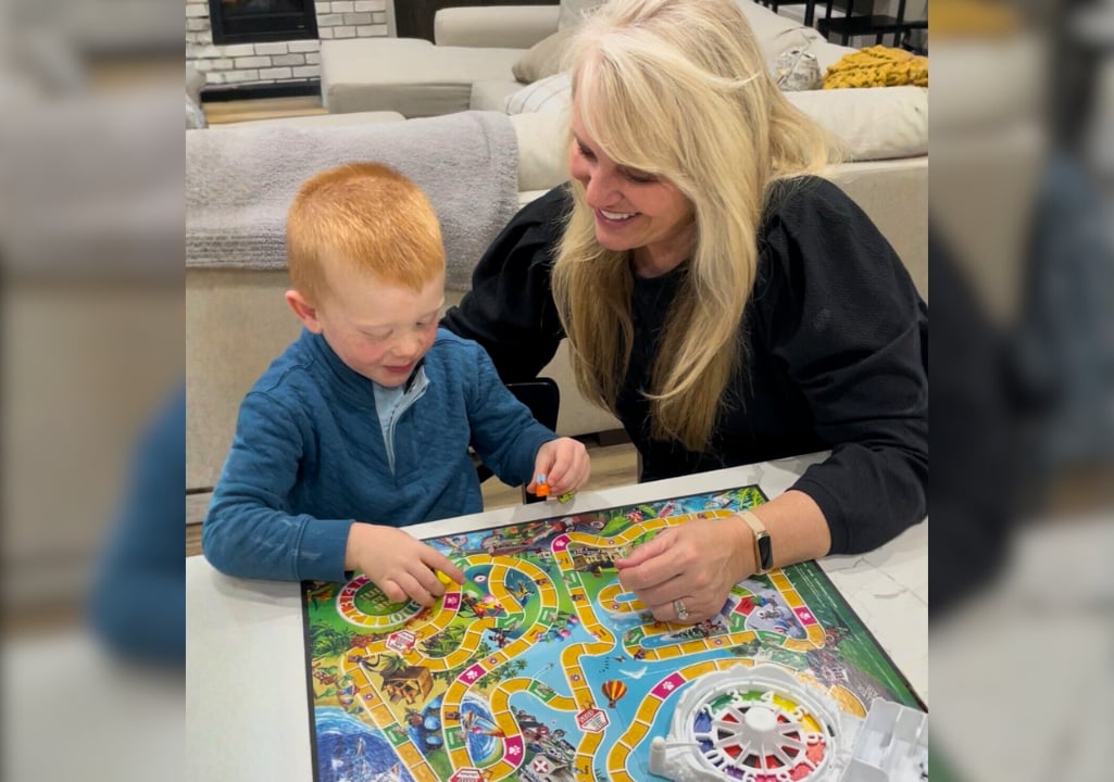 Sharla Ellis playing The Game of Life board game with her young grandson at home, sharing a joyful life lesson.