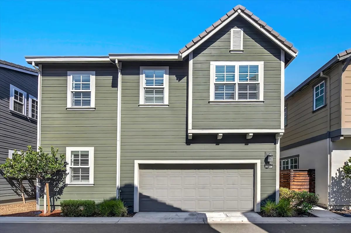 Two-story olive-gray home with white trim, a prominent gable, and an attached two-car garage.
