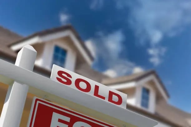 Sold sign in front of a two-story house.