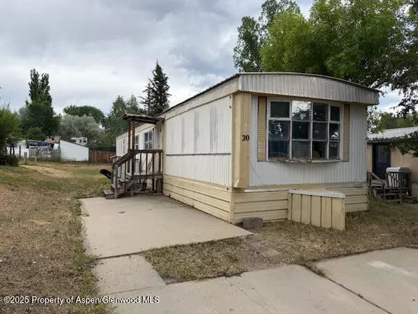 Small manufactured home with a raised front porch and concrete walkway.