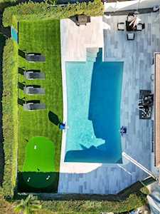 Backyard swimming pool beside a paved patio, outdoor dining area, and lawn.