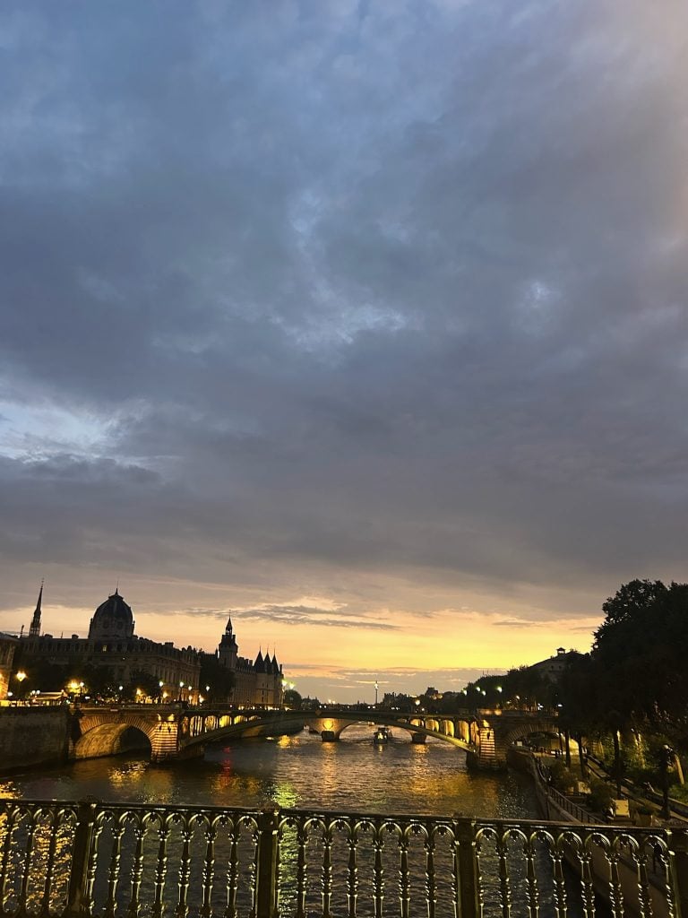The Seine at dusk in Paris, with illuminated bridges and city lights reflected on the water.