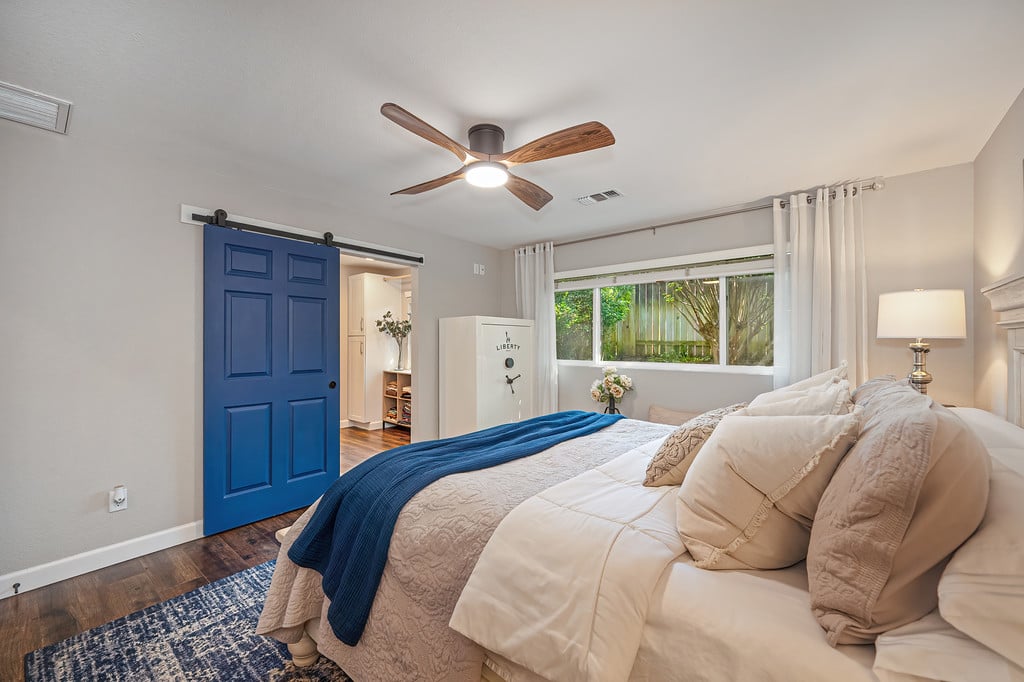 Bedroom with cream bedding, a blue throw, and a dark blue sliding barn door.