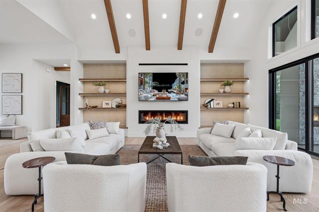 Living room with white sofas, built-in shelves, exposed beams, and a central fireplace.
