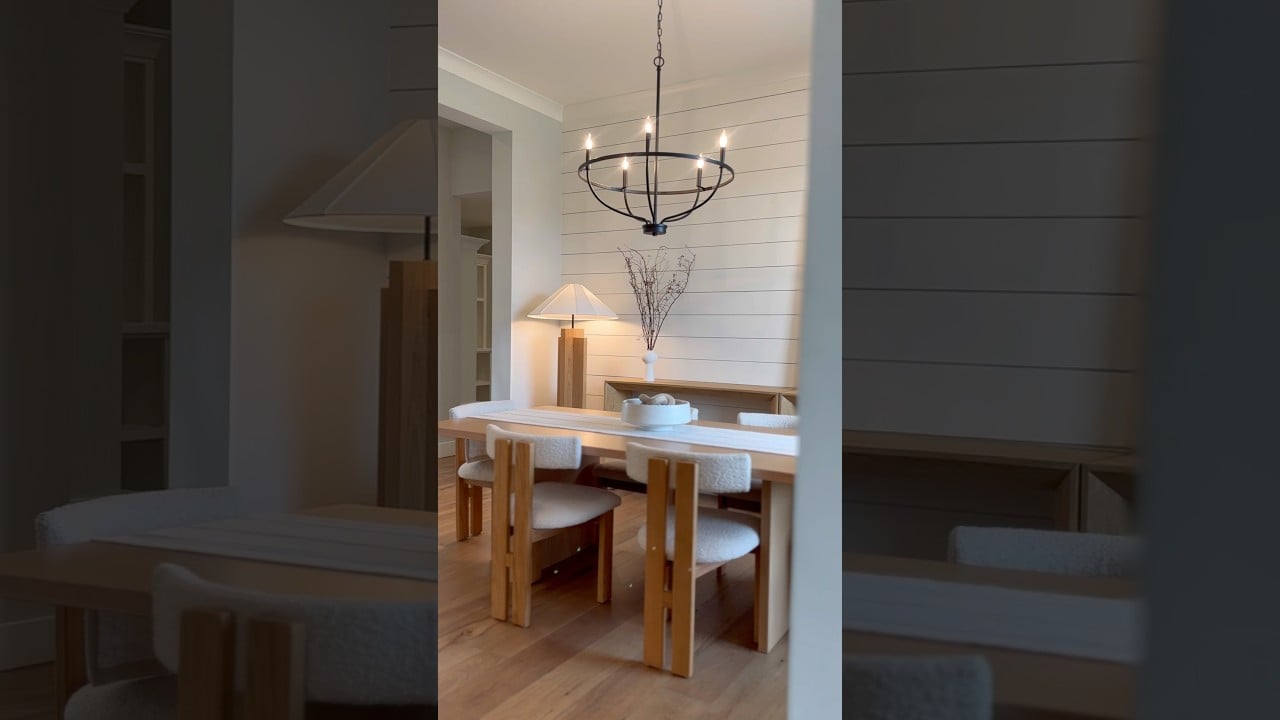Furnished dining room with a light wood table, upholstered chairs, and black circular chandelier.