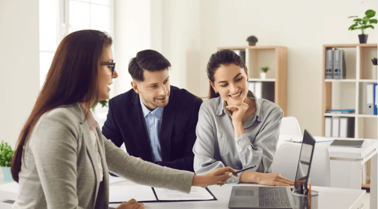 Real estate agent reviewing paperwork with a couple in a bright office.