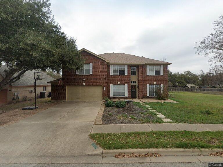 Two-story brick house with an attached garage and a broad concrete driveway.