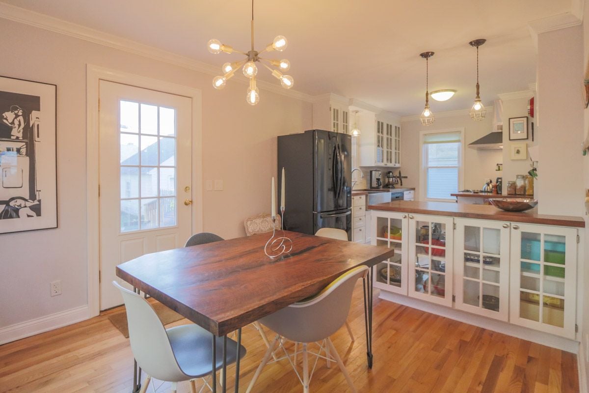 Kitchen and dining area with a large wooden table, white cabinets, and hardwood floors.