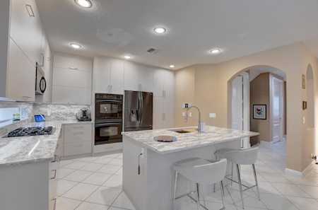 White kitchen with stainless steel appliances, a marble-patterned island, and an arched doorway.