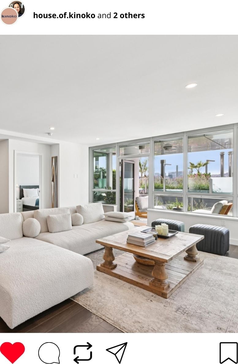 IG post: A bright living room with a white sectional sofa, a large wooden coffee table, and floor-to-ceiling windows.
