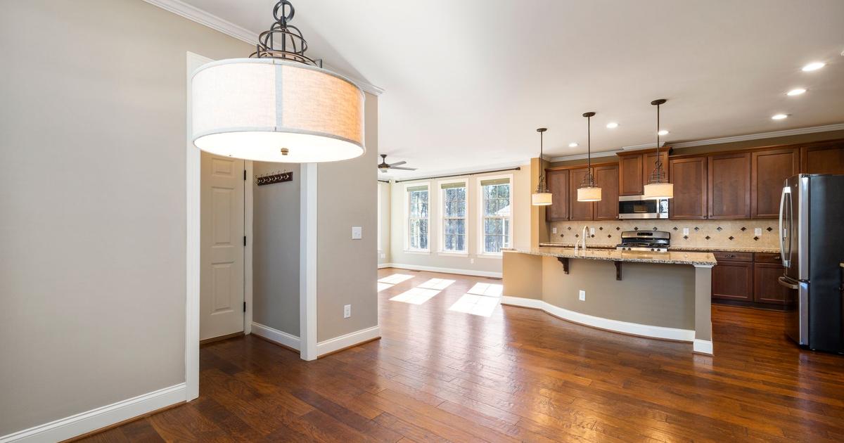 Open kitchen with a large breakfast bar, warm wood cabinets, and dark hardwood floors.