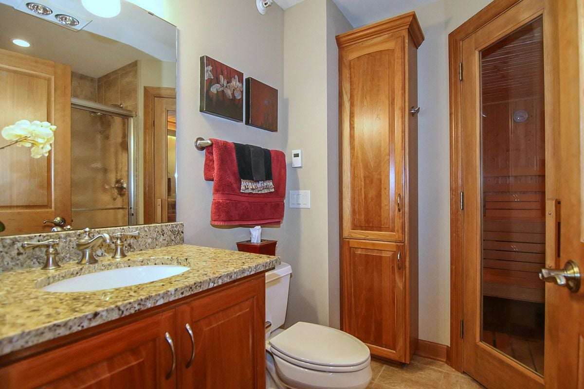 Bathroom with granite vanity and glass-doored wooden sauna
