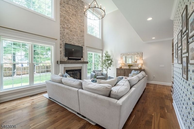 Living room with a white sectional, stone fireplace, vaulted ceiling, and tall windows.