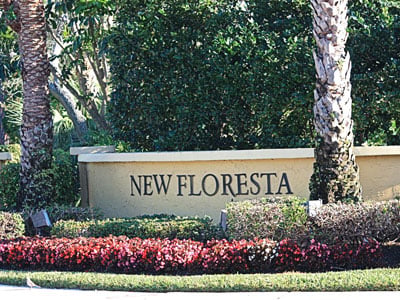 New Floresta neighborhood entrance sign among palms and flowering shrubs.