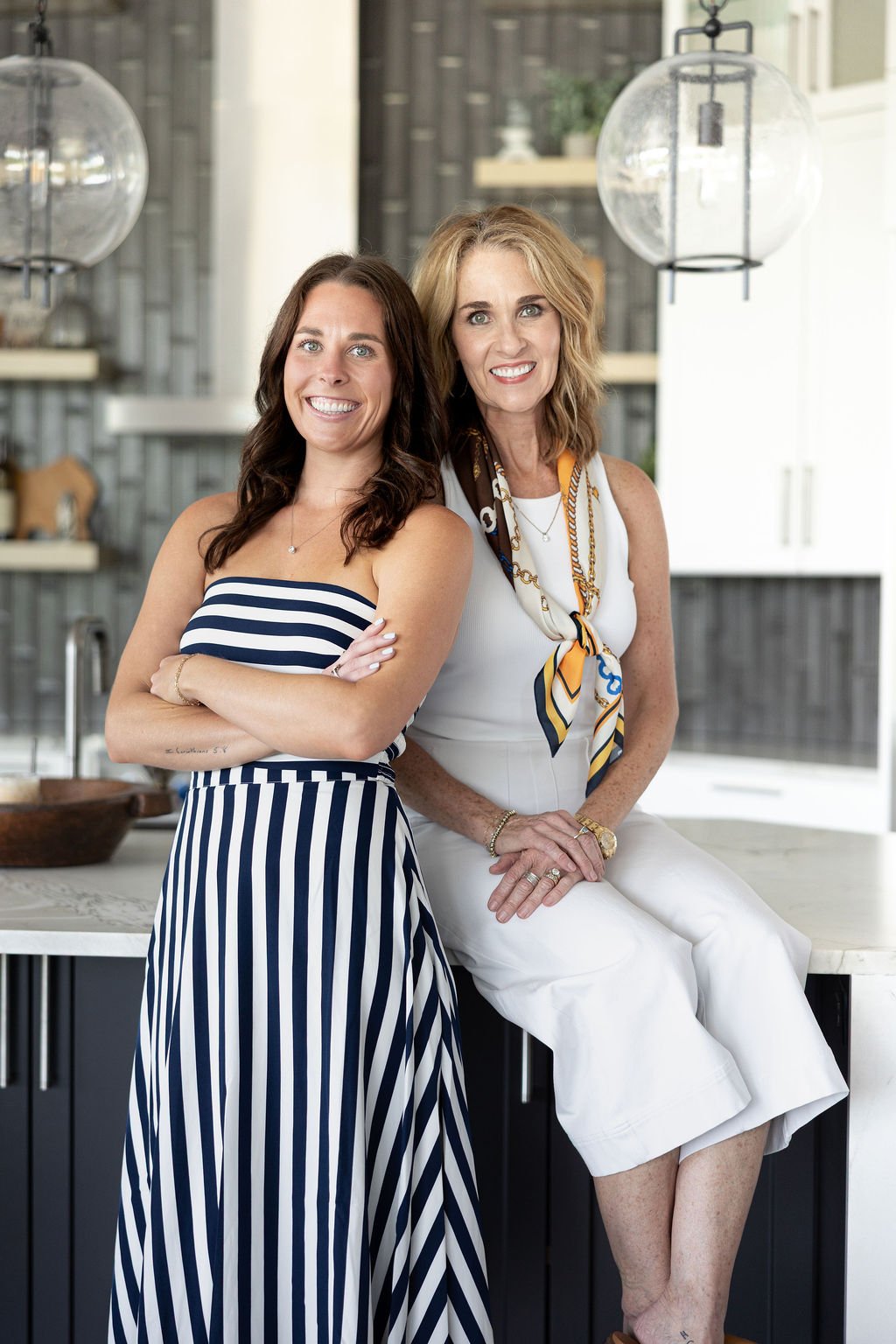 Two women pose together in a bright modern kitchen.