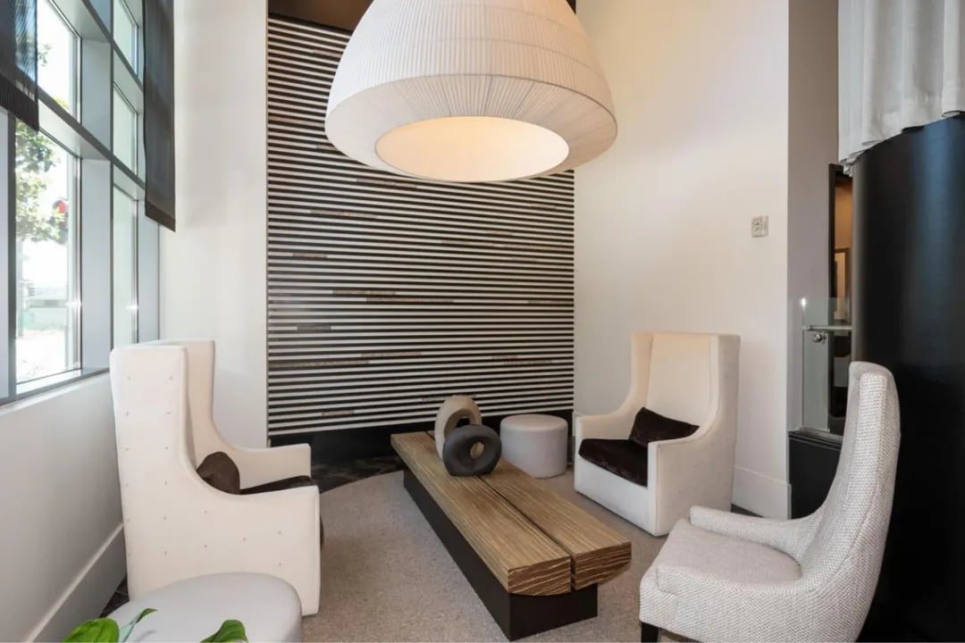 A stylish seating area in the Madrone building, featuring two wingback chairs and a wooden bench with unique decor.