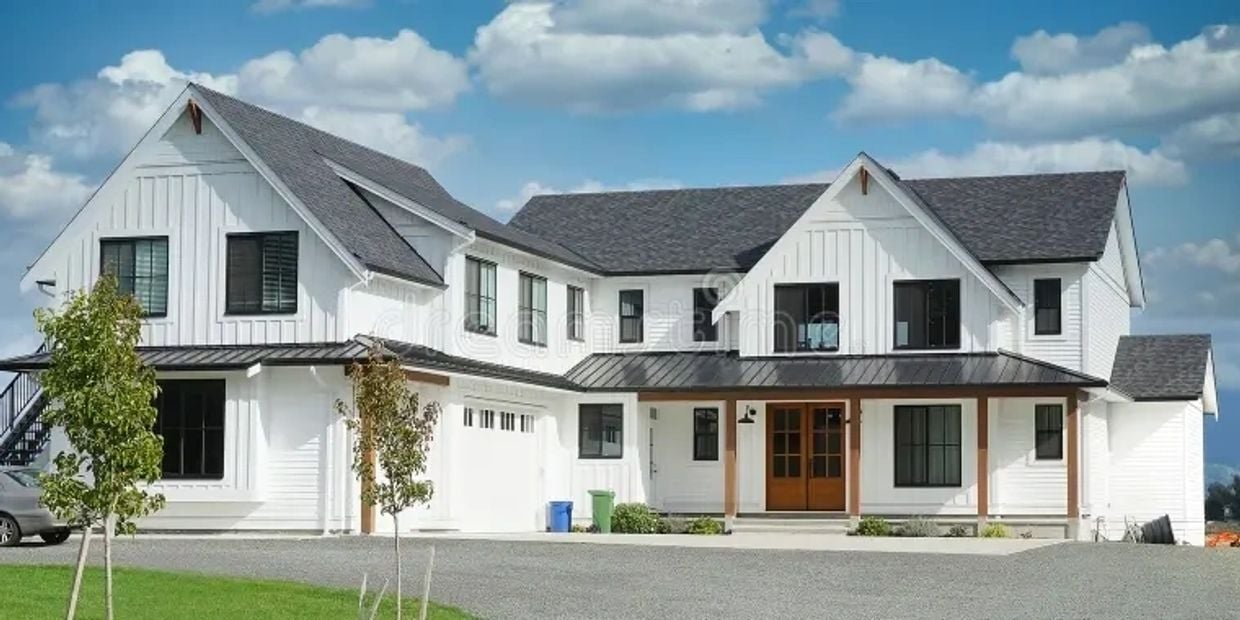 White modern farmhouse with multiple gables, black-framed windows, and a covered porch with a wood-and-glass front door.
