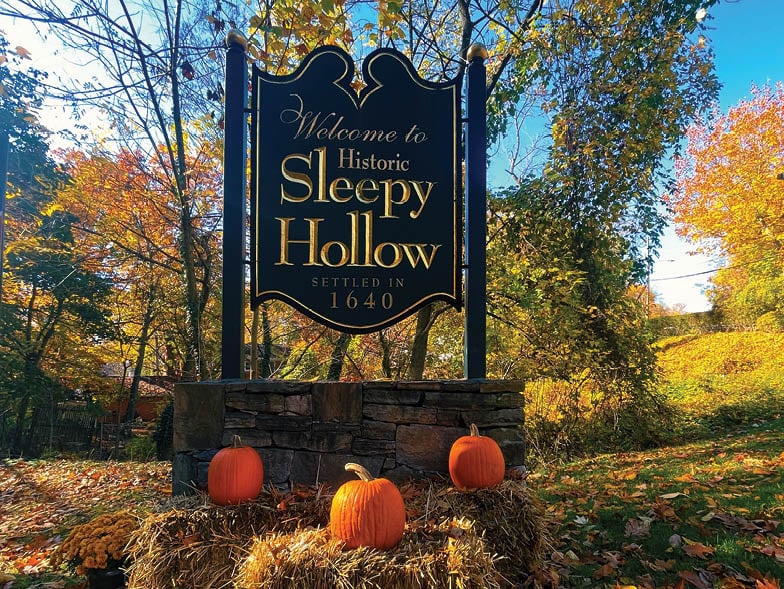 Historic Sleepy Hollow welcome sign with pumpkins and autumn foliage