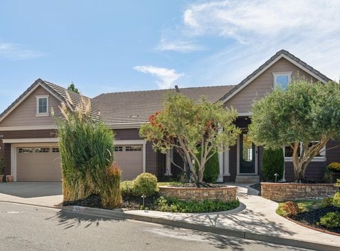 Single-story home with an attached garage, landscaped front yard, and curved walkway to the entrance.