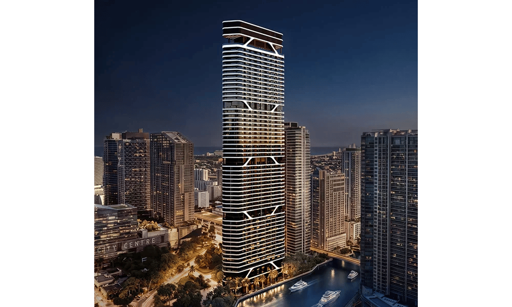 Rendering of a glass residential tower with illuminated white bands beside the water and Miami’s skyline at dusk.