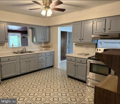 Kitchen with gray cabinets, an electric range, and a geometric-patterned floor.