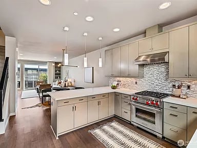 Bright kitchen with a large island, stainless steel range, patterned backsplash, and adjoining dining area.