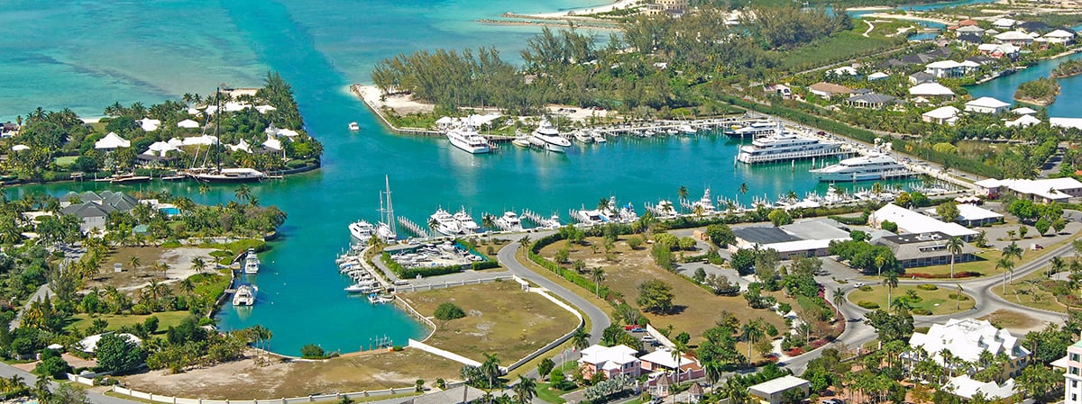 Aerial view of Lyford Cay’s marina, with yachts, waterfront homes, and turquoise channels.