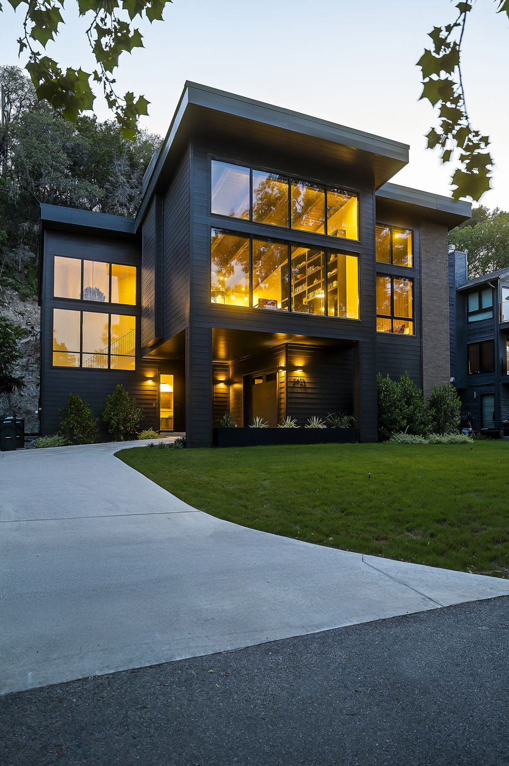 Twilight elevation with driveway and lawn, built by Pecan Valley Custom Homes and designed by Kelley Design Group. Lake Austin waterfront at 2403 Big Horn Drive, Austin.