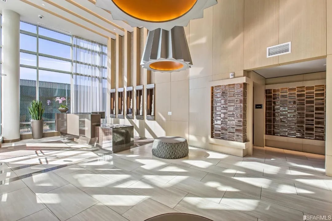 Arden Residences elegant lobby interior featuring modern pendant lighting, marble floors, floor-to-ceiling windows, and contemporary seating areas in Mission Bay