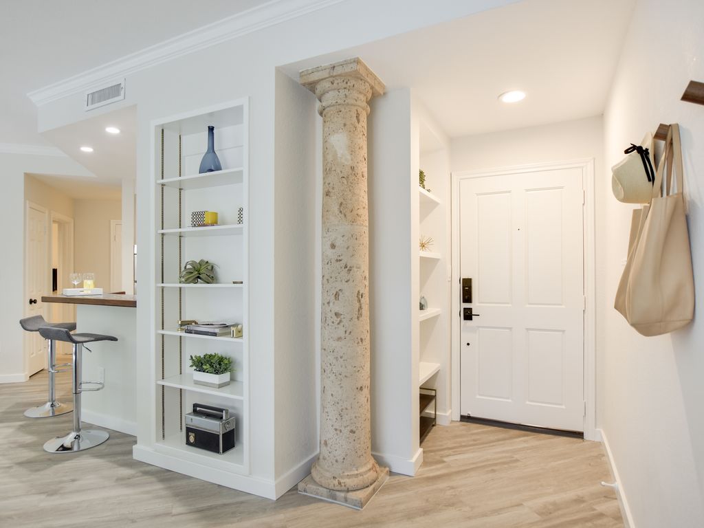 Entry foyer with a decorative stone column and built-in shelving at 1000 Liberty Park Drive #203, Liberty Park Condominiums, Westlake, Austin, TX 78746.