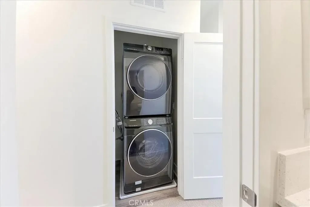  A laundry closet with a black stacked washer and dryer unit, seen through an open white door.