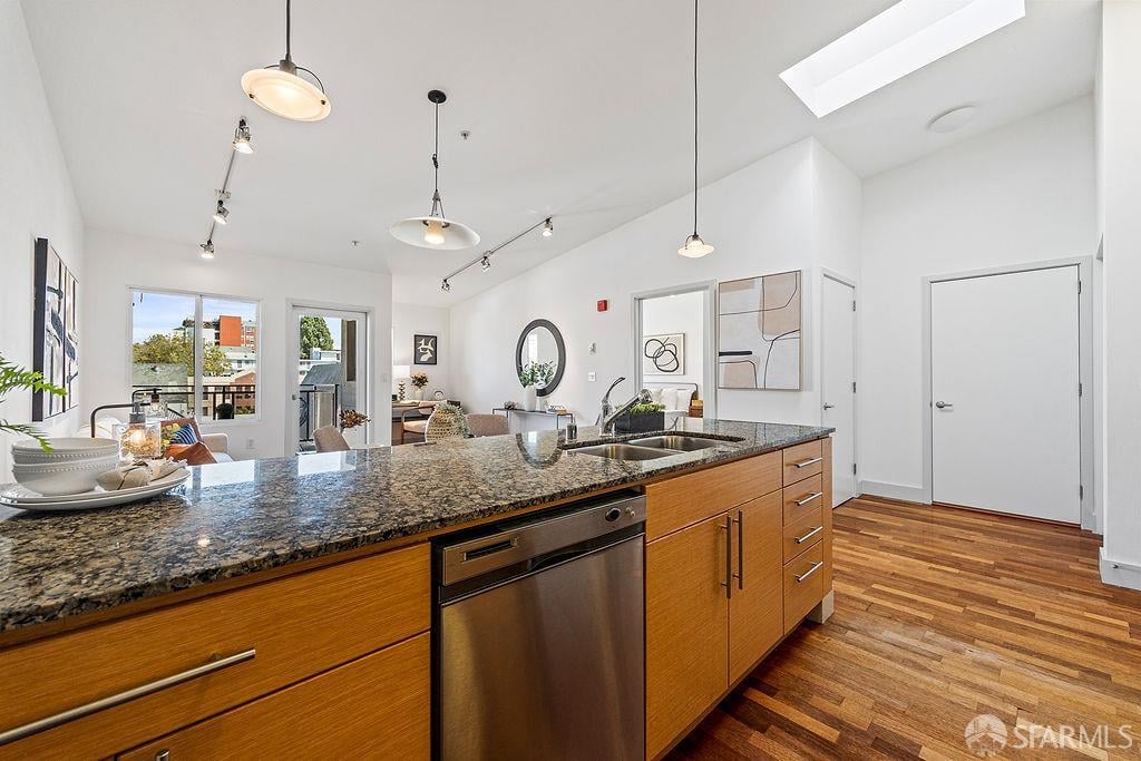 Open-plan kitchen with a granite island, warm wood cabinets, and hardwood floors.