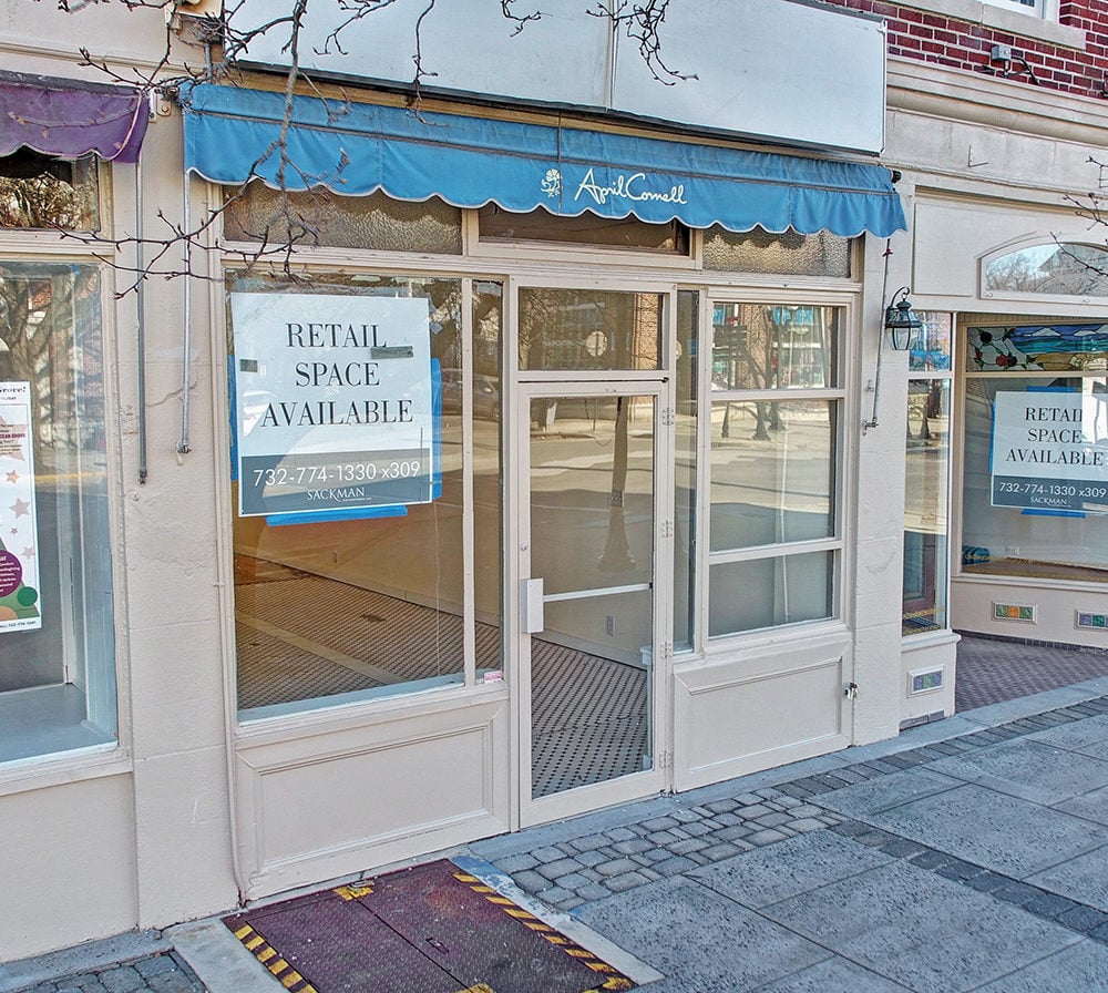 Vacant retail storefront with a blue April Cornell awning and signs advertising available space.