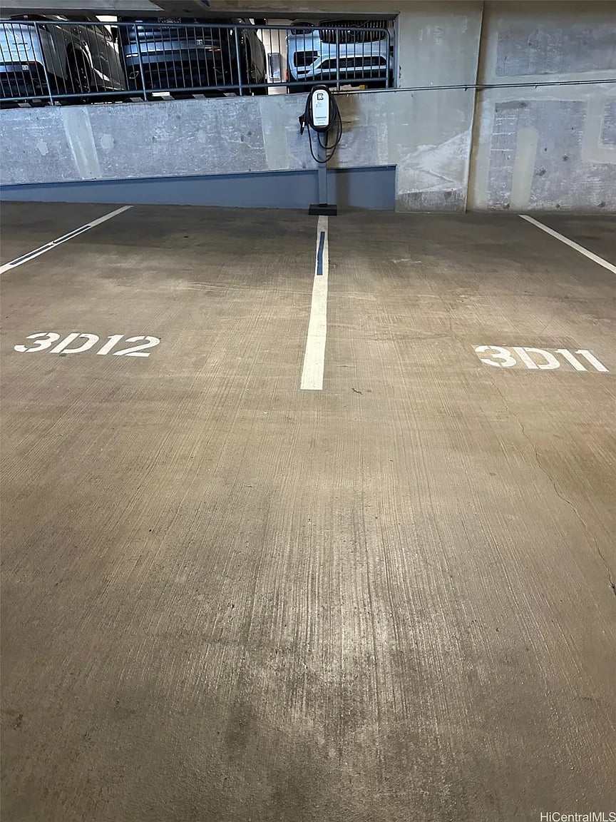 Two numbered garage parking spaces beside a wall-mounted electric vehicle charger.