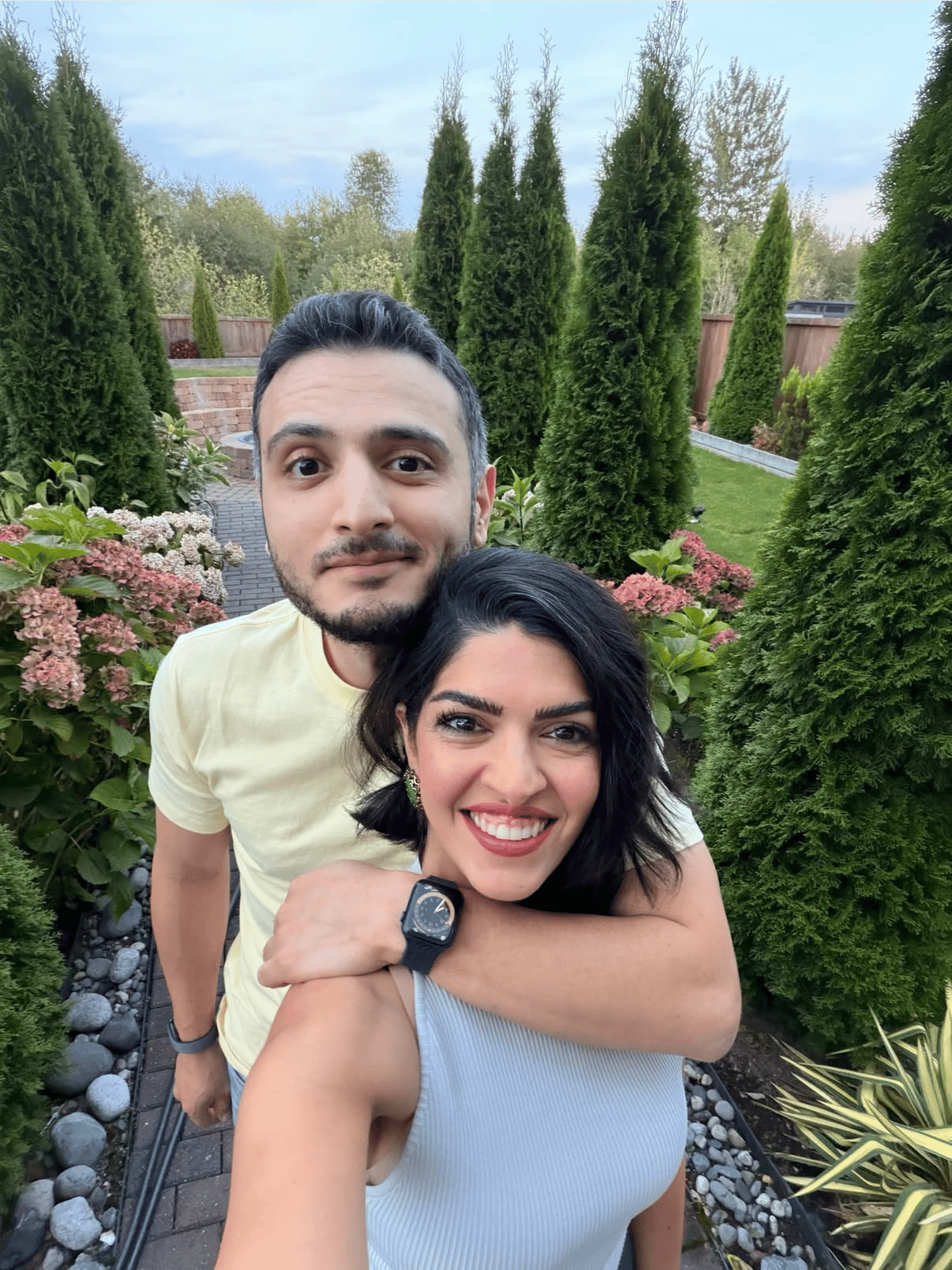 A couple poses together in a landscaped backyard garden.